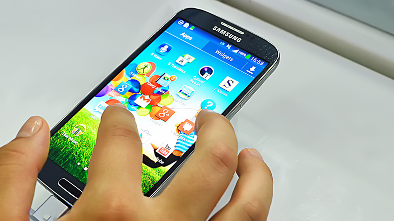 Hand selecting an app from the Samsung Galaxy S4 home screen