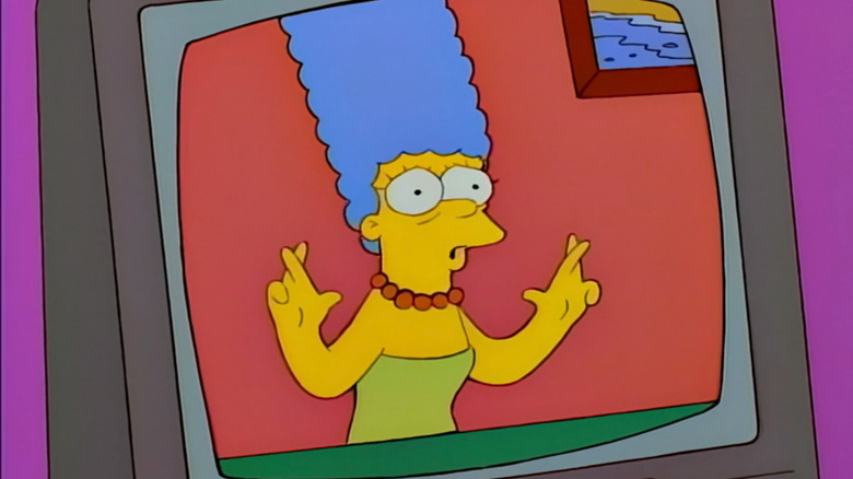 Marge Simpson with fingers crossed over a video phone