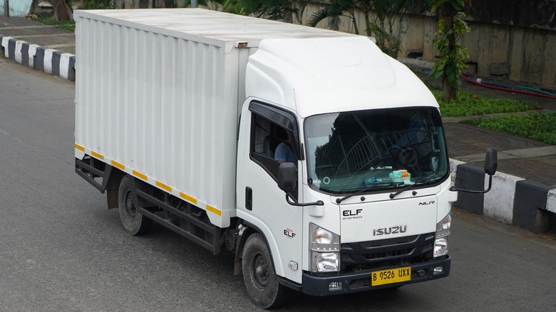 white isuzu elf truck driving street