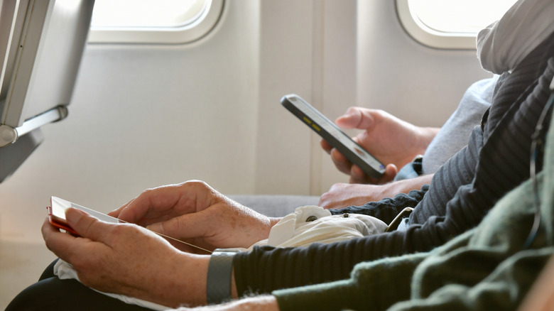 people using phones on plane