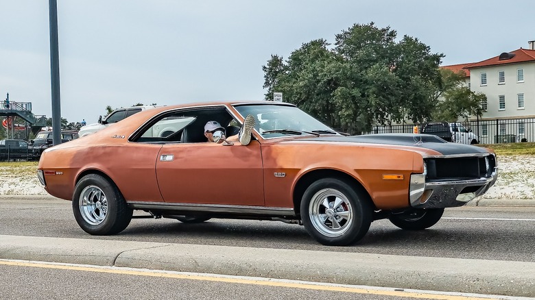 A brown AMC Javelin driving down a road