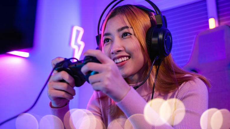 Woman playing on wired controller with headphones.