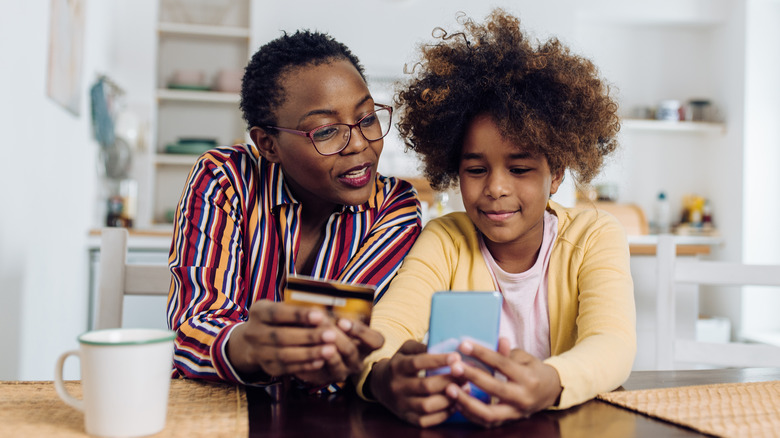 Parent and child with phone and credit card