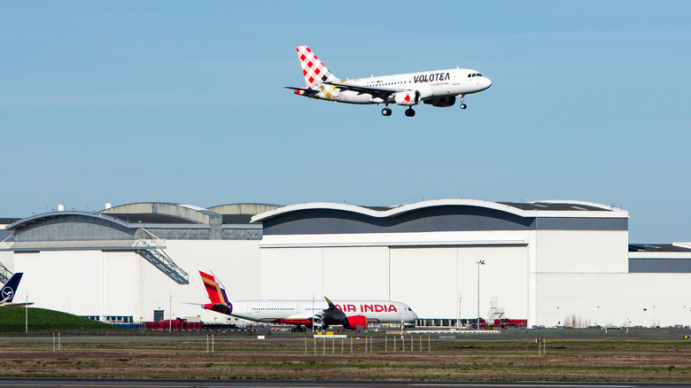 Airbus A320 in flight over buildings