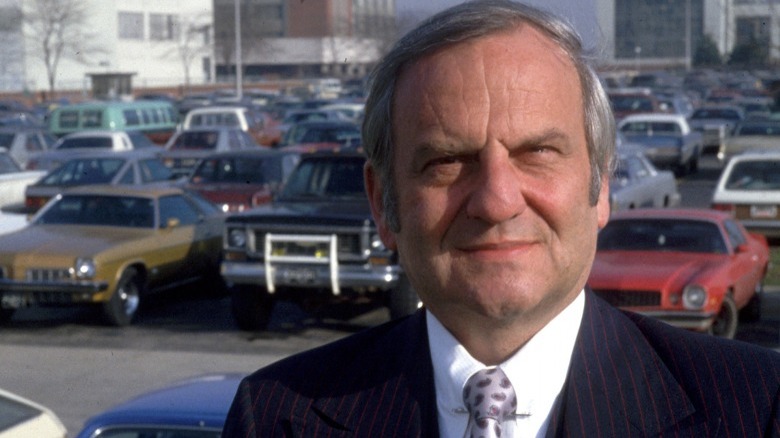 Lee Iacocca standing with a car park in the background