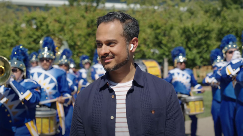 Man wearing AirPods with band in blue behind him.