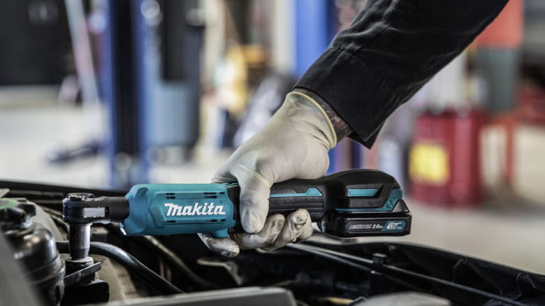 Person using a Makita tool on a vehicle