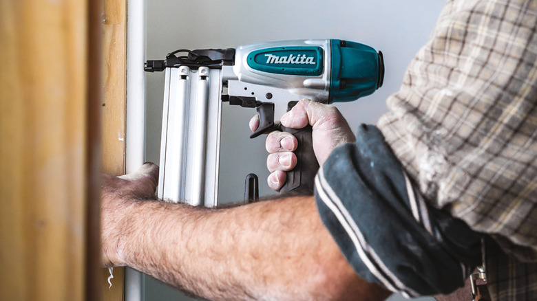 Person using a Makita brad nailer on wall