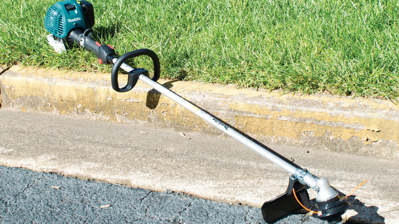 Gas-powered weed eater laying on the grass