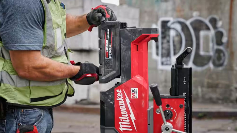 man inserting a Milwaukee FORGE battery into a large power tool