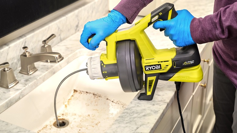 Person using Ryobi drain auger