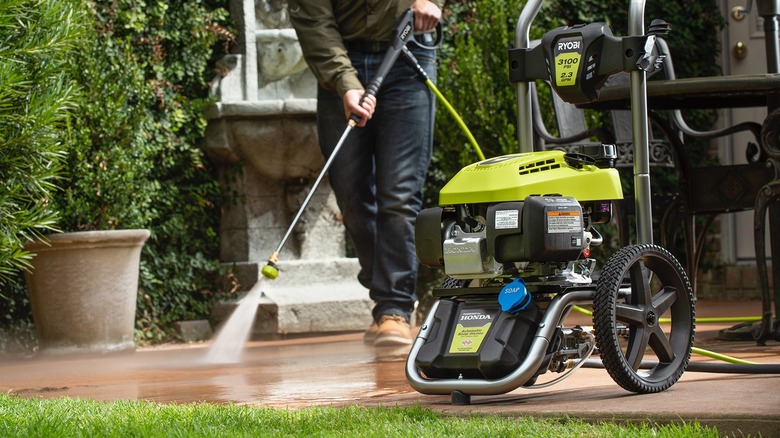 person using Ryobi gas pressure washer on outdoor tile