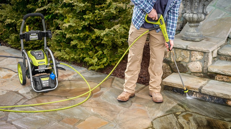 person using Ryboi electric pressure washer on stone walkway