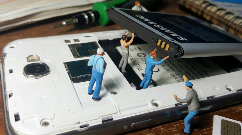 Miniature humans repairing a smartphone