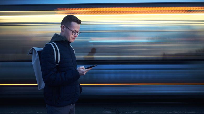 Man on smartphone before train