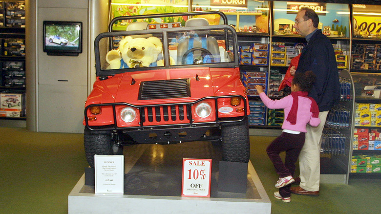 Father and child look at a toy Humvee for sale