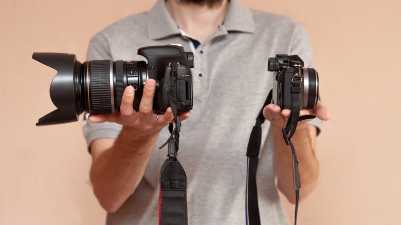 Person holding two different cameras