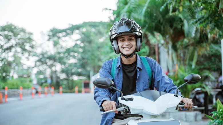 man riding motorcycle in street while smiling