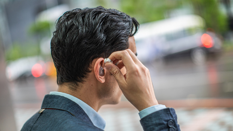 man putting on hearing aids