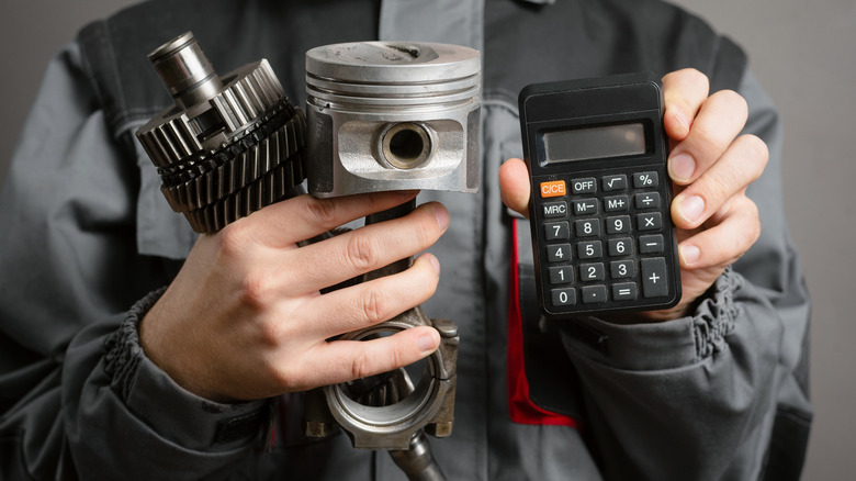 Man holding motorcycle parts and a calculator