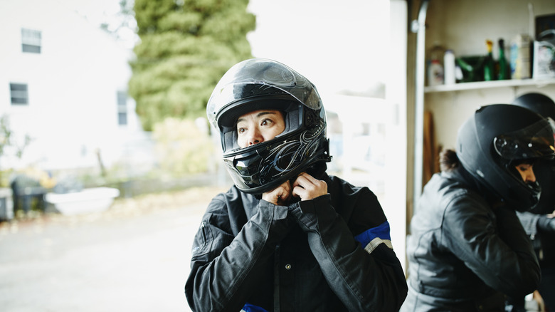 Woman putting on motorcycle helmet