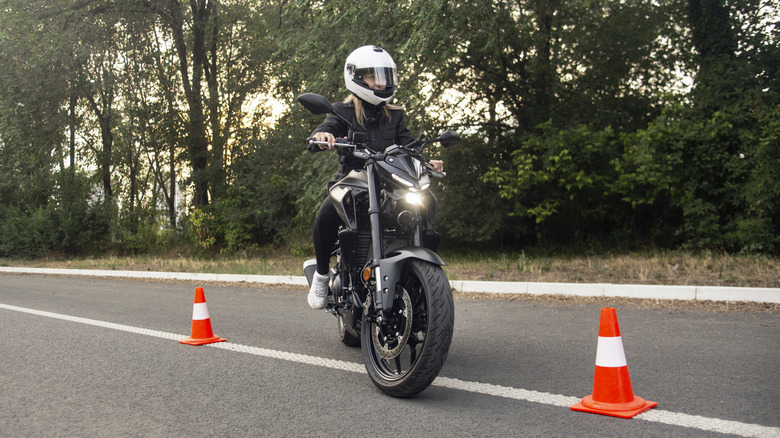 Young woman riding a motorcycle between traffic cones