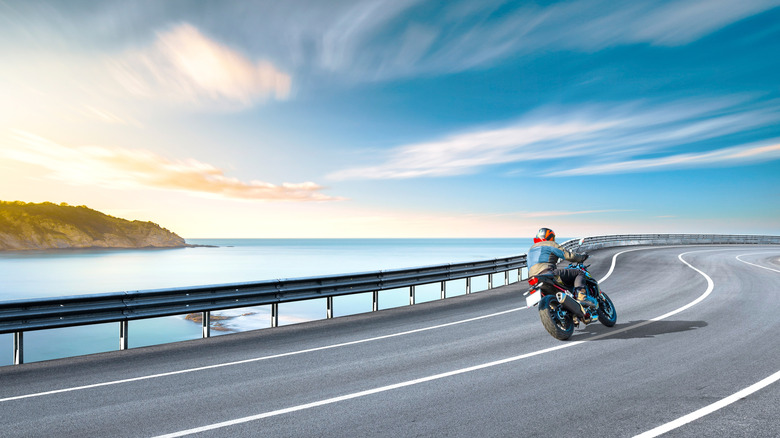 Man riding a motorcycle on a clifftop road