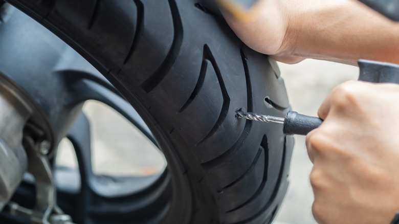 Person repairing punctured motorcycle tire