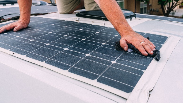 Man cleaning solar panel on roof 