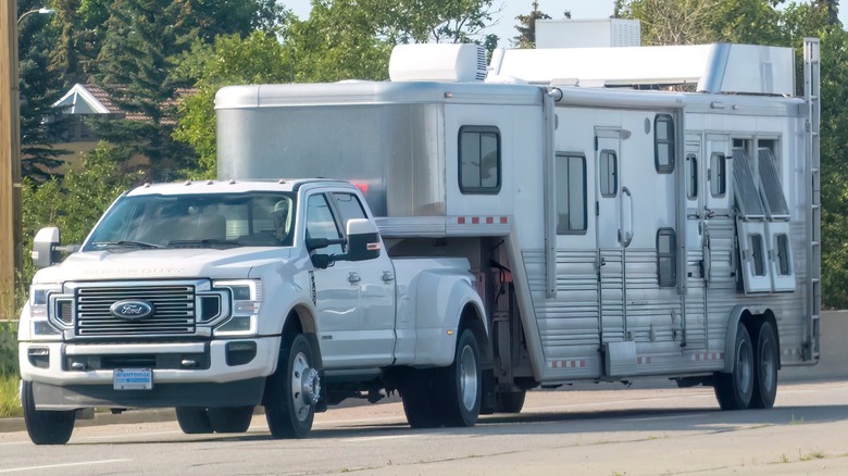 A Ford Super Duty towing a large stock trailer with living quarters