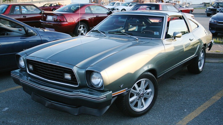 Green Ford Mustang II with custom wheels parked on tarmac