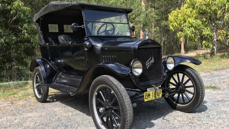 1925 Ford Model T Touring Car parked on gravel in front of woods