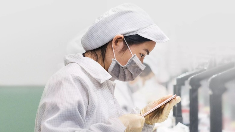 Apple factory worker inspecting iPhone