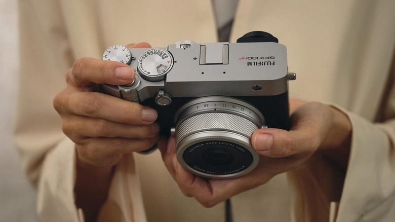 Person holding the Fujifilm GFX100RF camera.