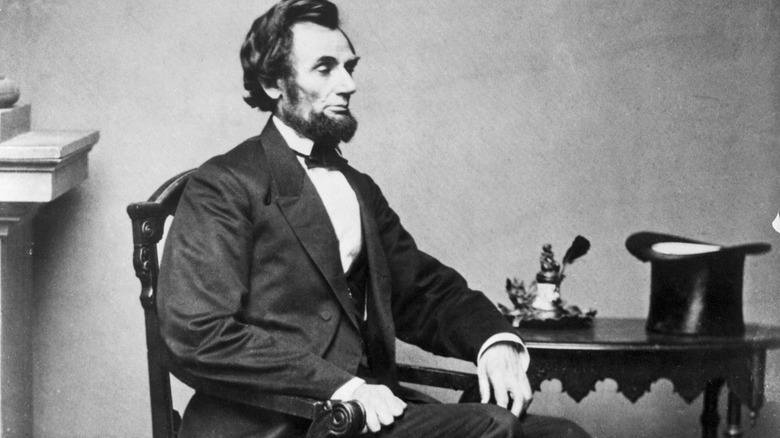 Black and white photo of Abraham Lincoln seated next to a table in 1861