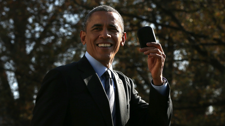 President Barack Obama holds up his Blackberry after he ran back into the White House after forgetting the mobile phone while departing for a domestic trip November 21, 2014 in Washington, DC.