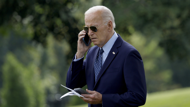 President Joe Biden looks at his phone as he leaves the White House on August 16, 2024 in Washington, DC.