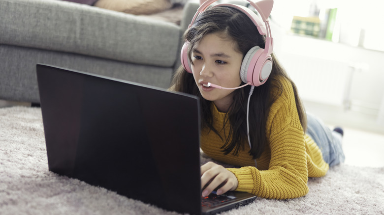 Person playing gaming laptop on the floor