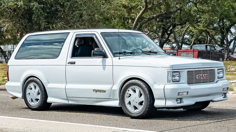 A white GMC Typhoon is pictured against a background of oak trees.