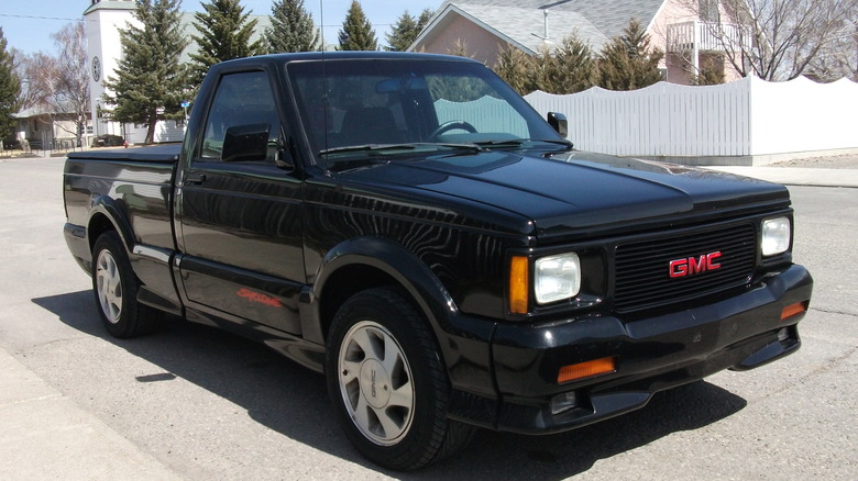 A black GMC Syclone is pictured parked on a street in a residential neighborhood.