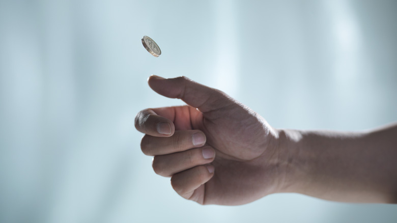 Someone tossing a coin with their hand