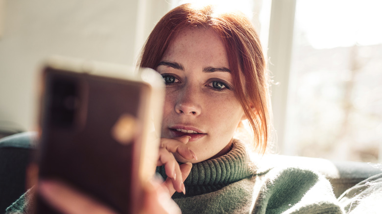 A woman is looking at the screen of her mobile phone