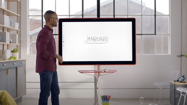 A man presenting the Jamboard whiteboard inside an office