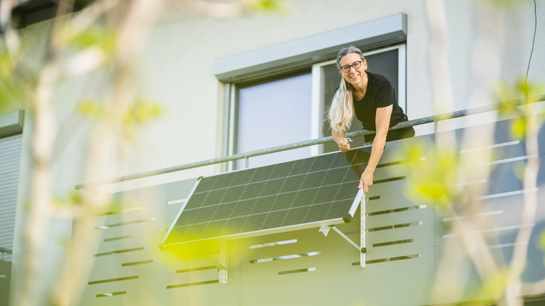 Person grabbing solar panel from window