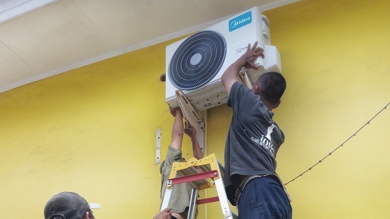 Men setting up fan on ladder