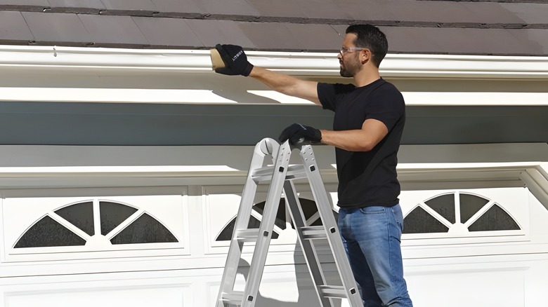 Man on ladder tending to roof