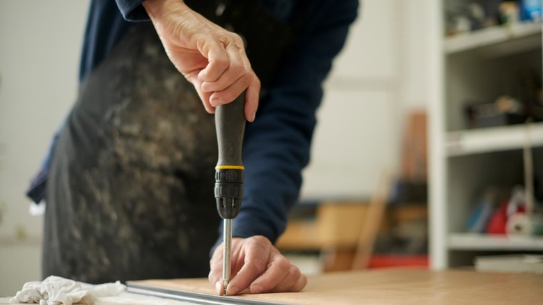 Man using screwdriver on wood