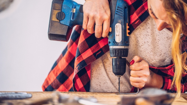 Woman using drill to drill into wood