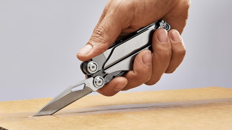 Person using multi-tool blade to cut a box open