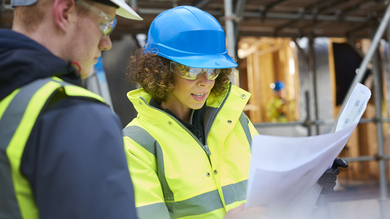 Worker in blue hard hat looking at plans